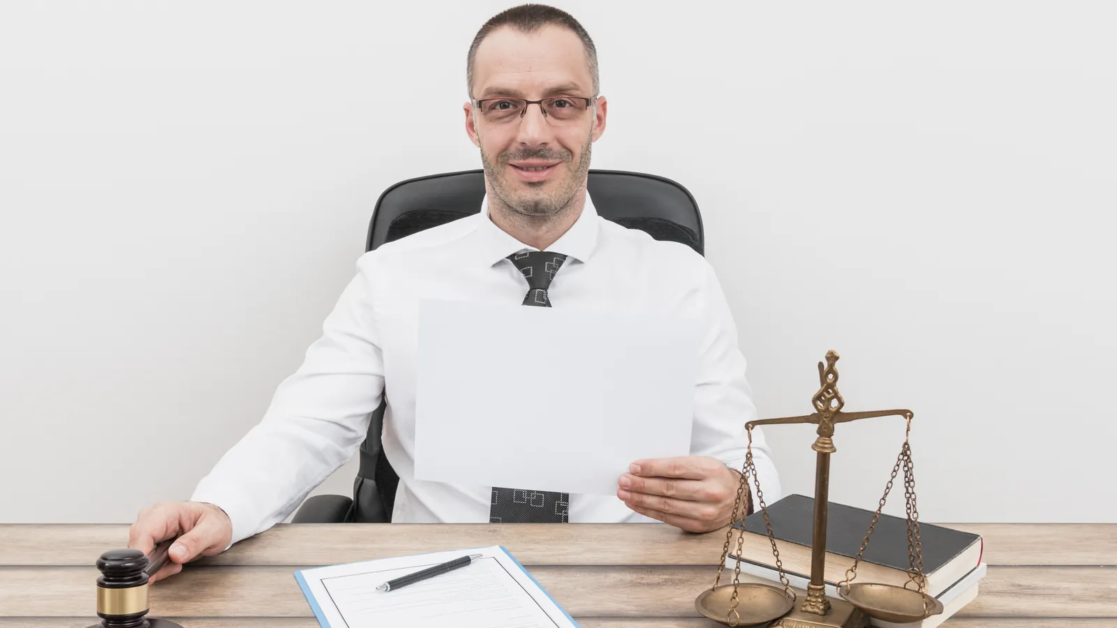 Advogado sentado à mesa do escritório segurando uma folha de papel